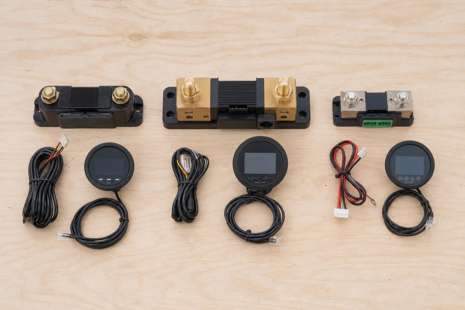 Three battery monitor shunt models compared side by side on workbench