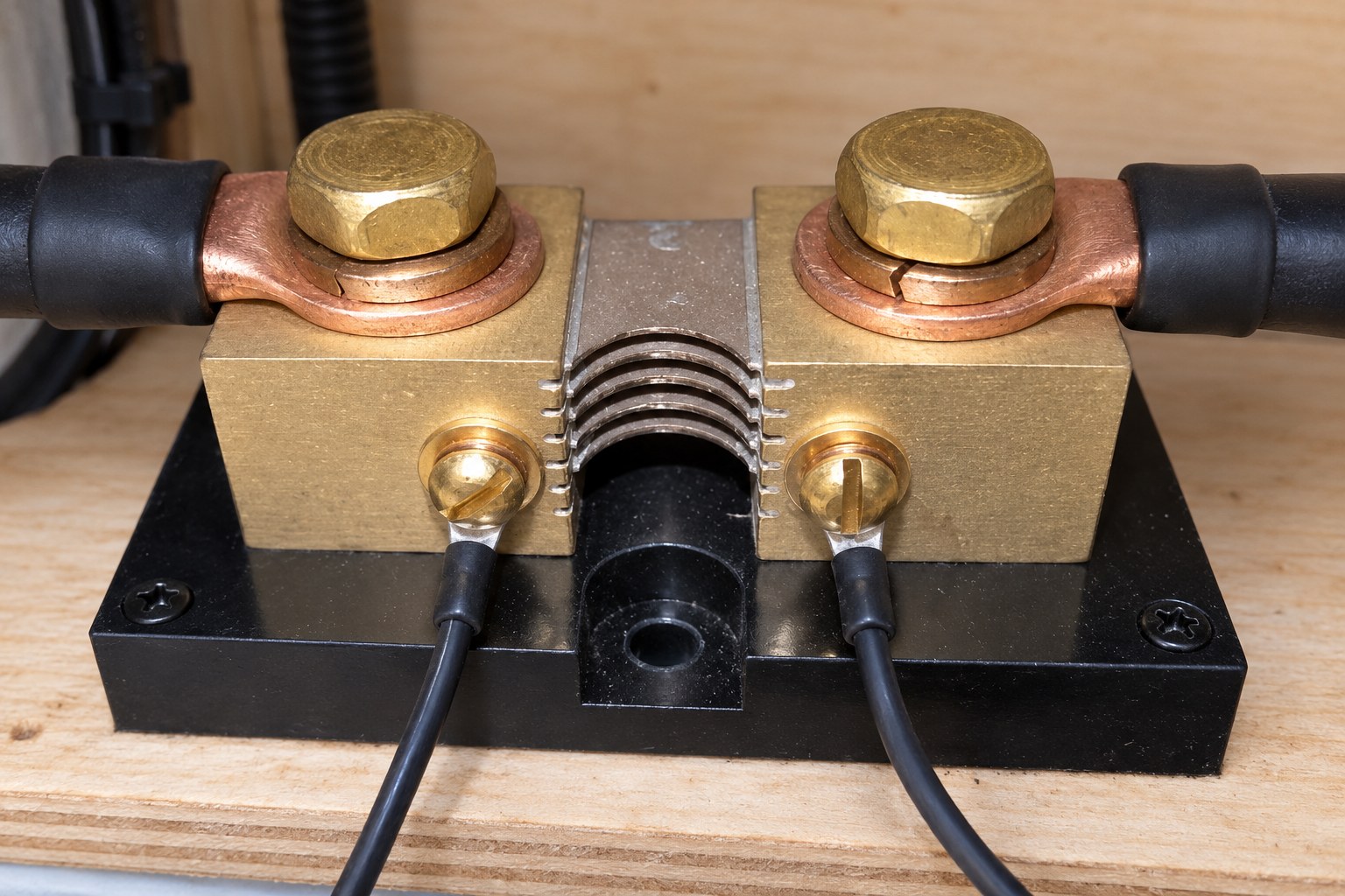 Two copper cable lugs bolted flat to brass shunt terminals, with small sensing wires attached to the front screws